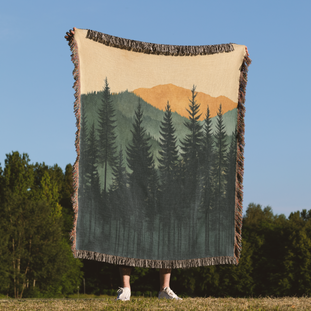 a person holding a blanket with a forest scene on it