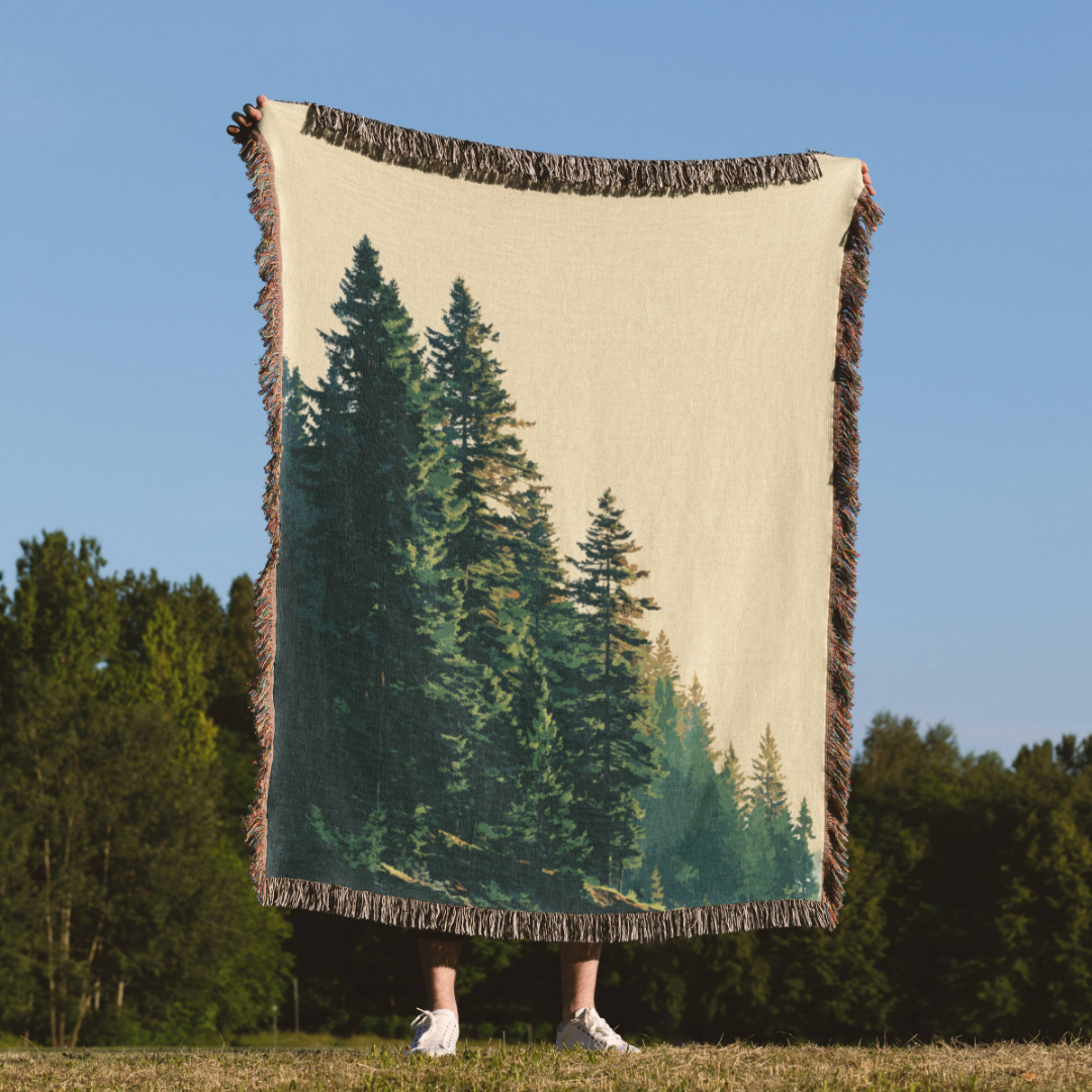a person holding a blanket with a picture of trees on it