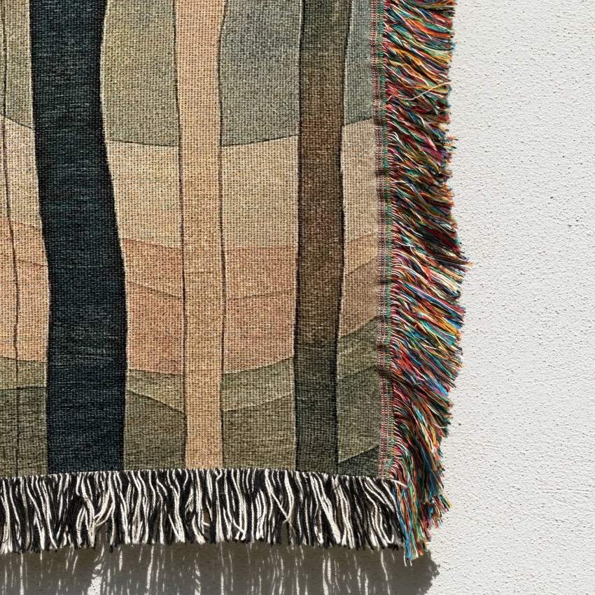 Textured woven blanket with colorful fringe on a white background
